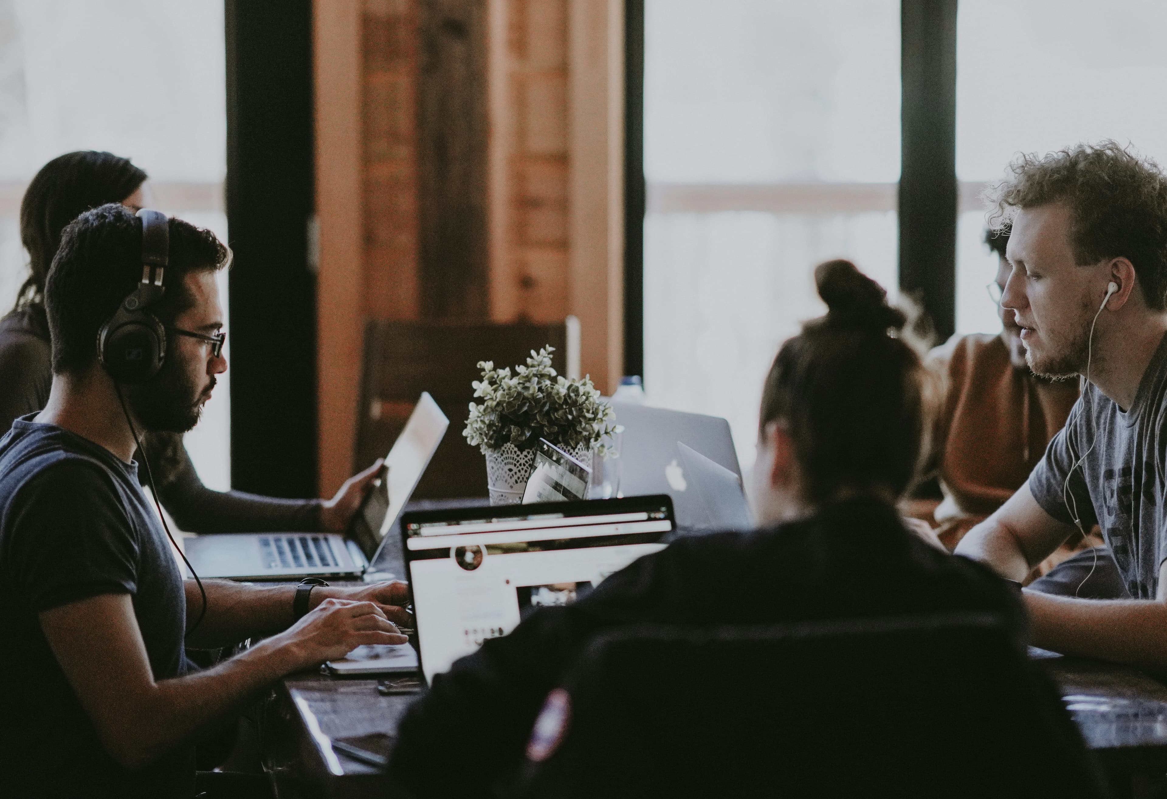 Team arbeitet gemeinsam mit Laptops an einem Tisch